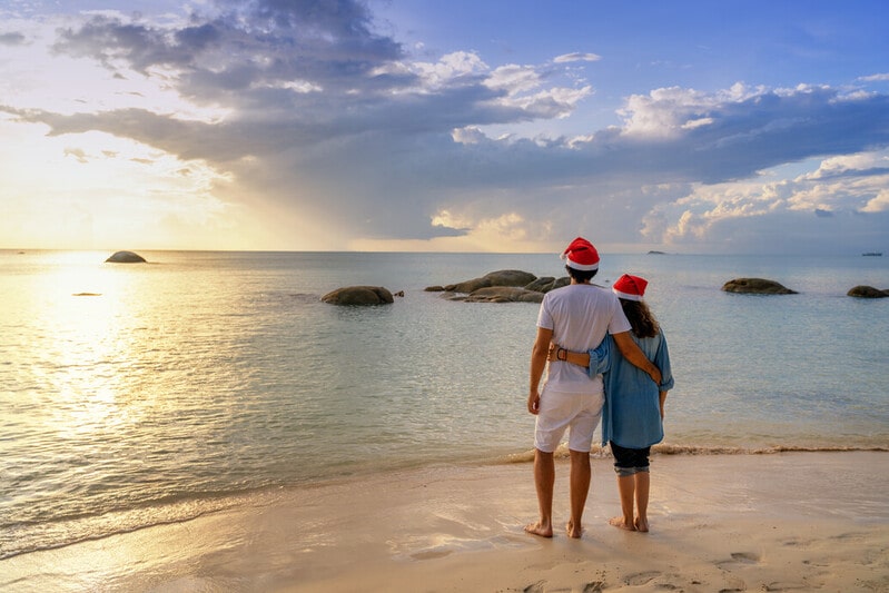 couple on beach with christmas hats