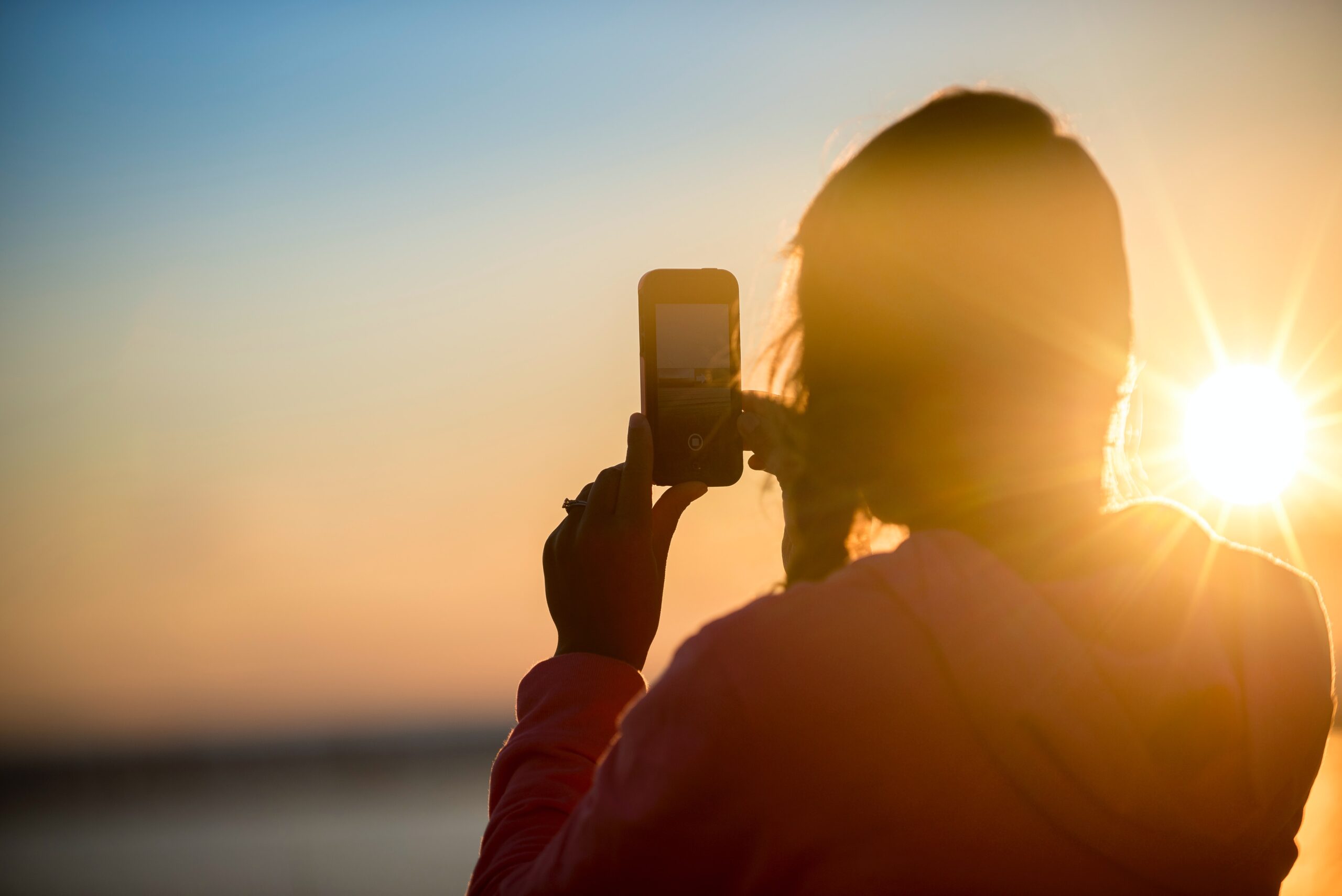 woman taking sunset photo